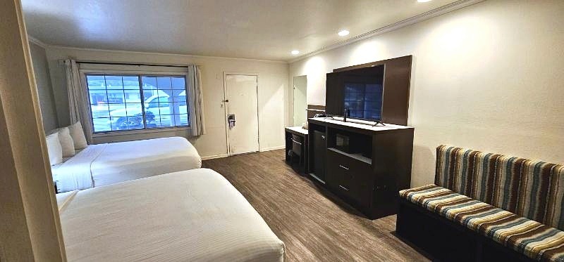 Double queen guest room with white bedding and seating bench